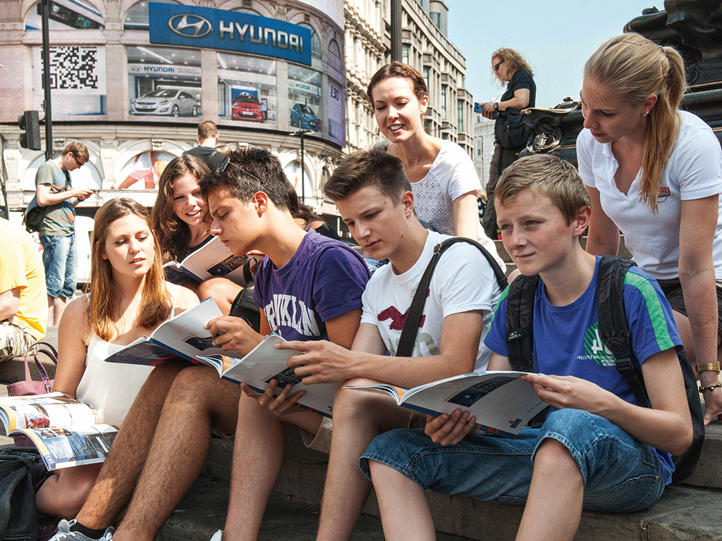 Auf dem Bild siehst du wie Kinder während ihrer Gruppenreise spaß haben. Sie machen während ihrer Stadtbesichtigung eine Pause.