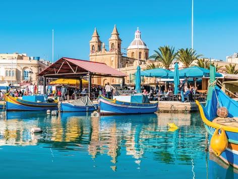 Bunte Fischerboote und Cafés am Wasser auf dem Marsaxlokk-Markt in Malta.