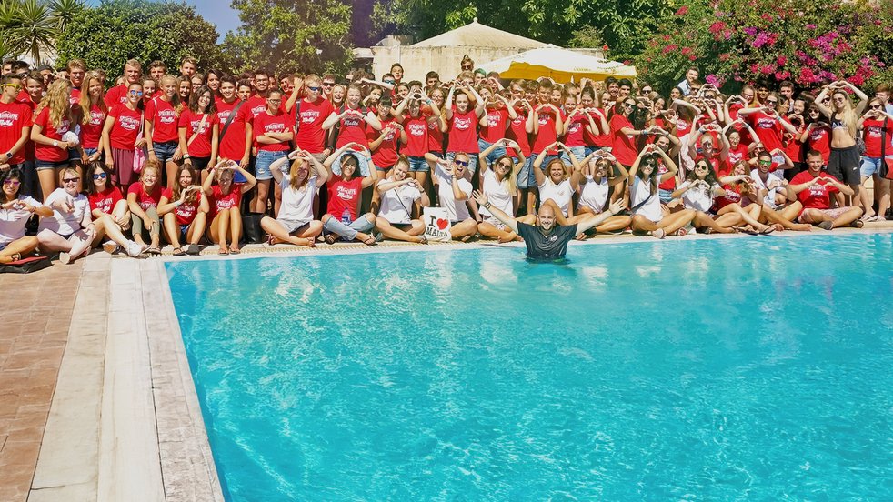 Eine große Gruppe von Sprachcaffe-Schülerinnen und -Schülern auf Malta posiert am Pool, viele bilden mit ihren Händen Herzformen.