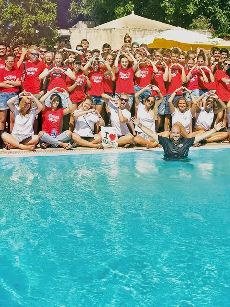 Eine große Gruppe von Sprachcaffe-Schülerinnen und -Schülern auf Malta posiert am Pool, viele bilden mit ihren Händen Herzformen.