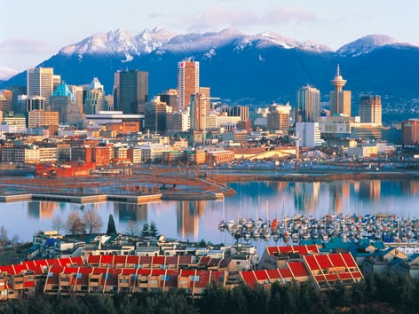 Die Skyline von Downtown Vancouver mit verschneiten Bergen und dem Hafen im Hintergrund.