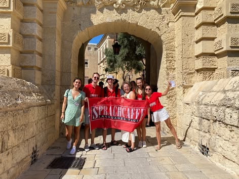 Schüler mit Sprachcaffe-Flagge am Mdina Gate, Malta.