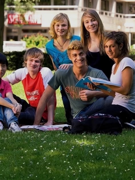 Eine Gruppe von Sprachcaffe-Juniorschülern sitzt auf der Wiese in Frankfurt, Deutschland, und genießt den sonnigen Tag.
