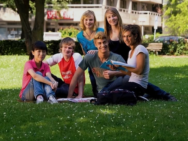 Eine Gruppe von Sprachcaffe-Juniorschülern sitzt auf der Wiese in Frankfurt, Deutschland, und genießt den sonnigen Tag.