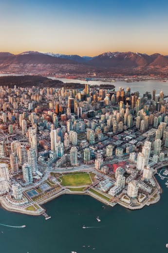 Aerial view of downtown Vancouver, Canada, with surrounding mountains, harbours, and bridges at sunset.