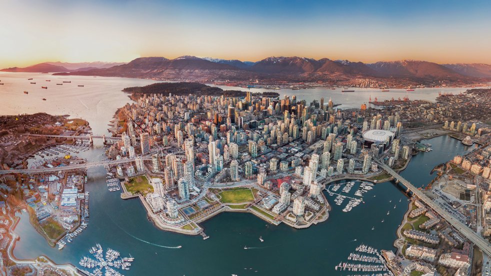 Luftaufnahme der Innenstadt von Vancouver, Kanada, mit den umliegenden Bergen, Häfen und Brücken bei Sonnenuntergang.