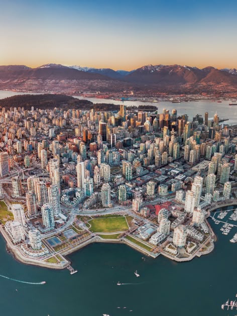Aerial view of downtown Vancouver, Canada, with surrounding mountains, harbours, and bridges at sunset.