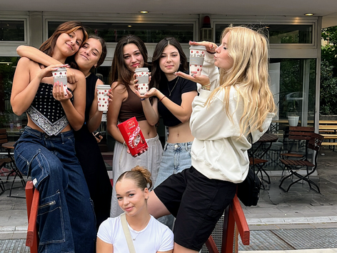 Eine Gruppe von Schülerinnen posiert mit Getränken vor einer Sprachcaffe-Sprachschule.