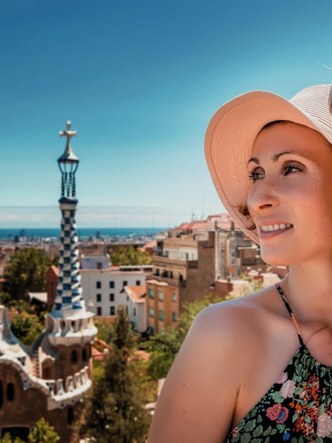 Smiling couple enjoying the view from Park Güell in Barcelona, Spain, with the city and sea in the background.