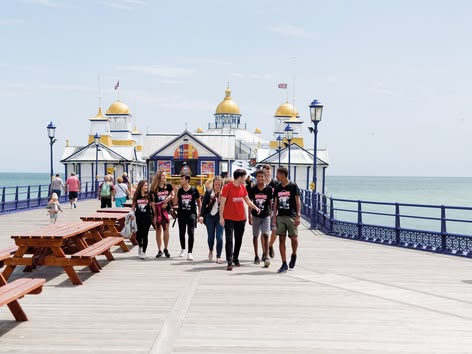 Sprachcaffe-Schülerinnen und -Schüler spazieren am Eastbourne Pier am Meer entlang.