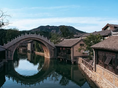 Traditionelle gewölbte Steinbrücke, die sich im Kanal der Wasserstadt Wuzhen, China, spiegelt.