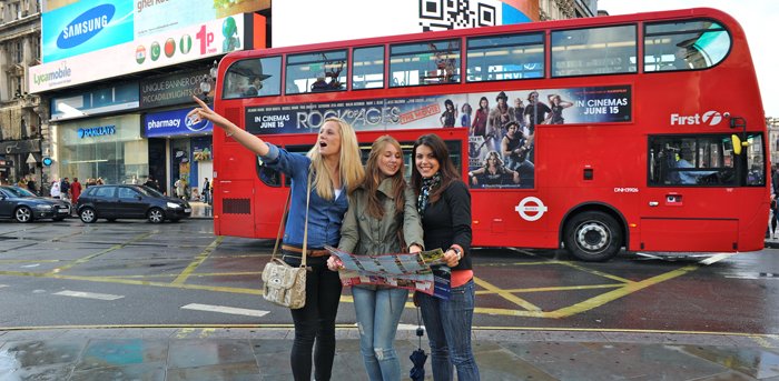 Lerne Englisch in London oder vielen weiteren spannenden englischsprachigen Reisezielen. Hier sind drei Frauen auf einer Sprachreise in London zu sehen. Im Hintergrund ist der typisch rote Bus aus London