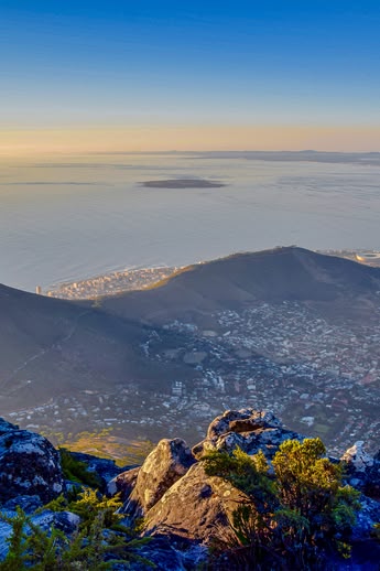 Panoramic view of Cape Town, South Africa, from Table Mountain with Lion's Head and the coastline below at sunrise.