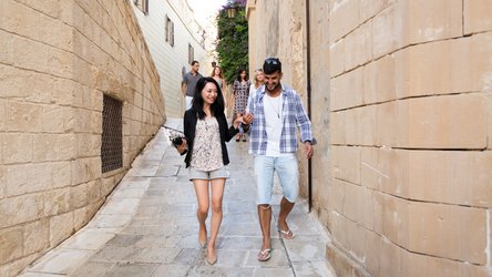 Auf dem Bild befinden sich zwei Personen auf einem Date in Malta. Sie genießen einen Spaziergang durch die Gassen.