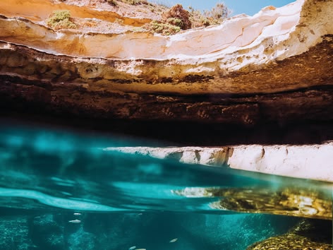 Ein Teenager springt von einer Felsklippe in einen natürlichen Pool.