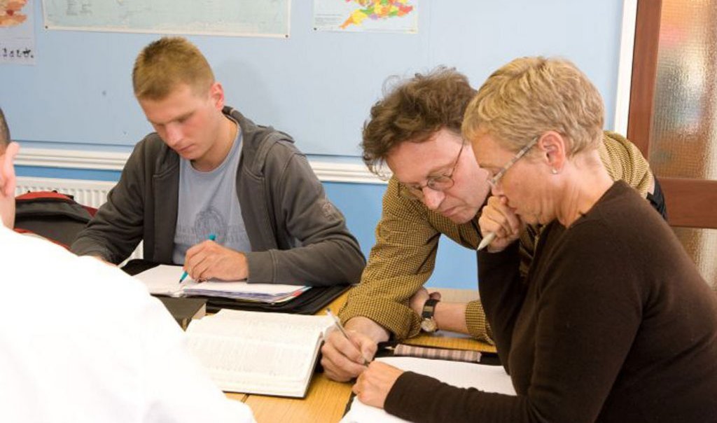 Hier lernen Sprachschüler die Kommasetzung in Englisch. Sie sitzen im Klassenraum konzentriert.